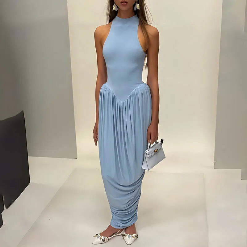 Woman wearing a light blue halter neck dress with a plain background