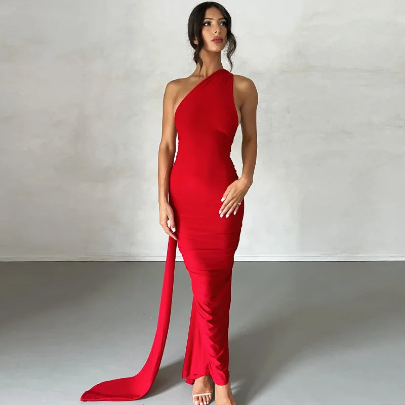 Woman wearing a red one-shoulder dress with a long train on a plain background