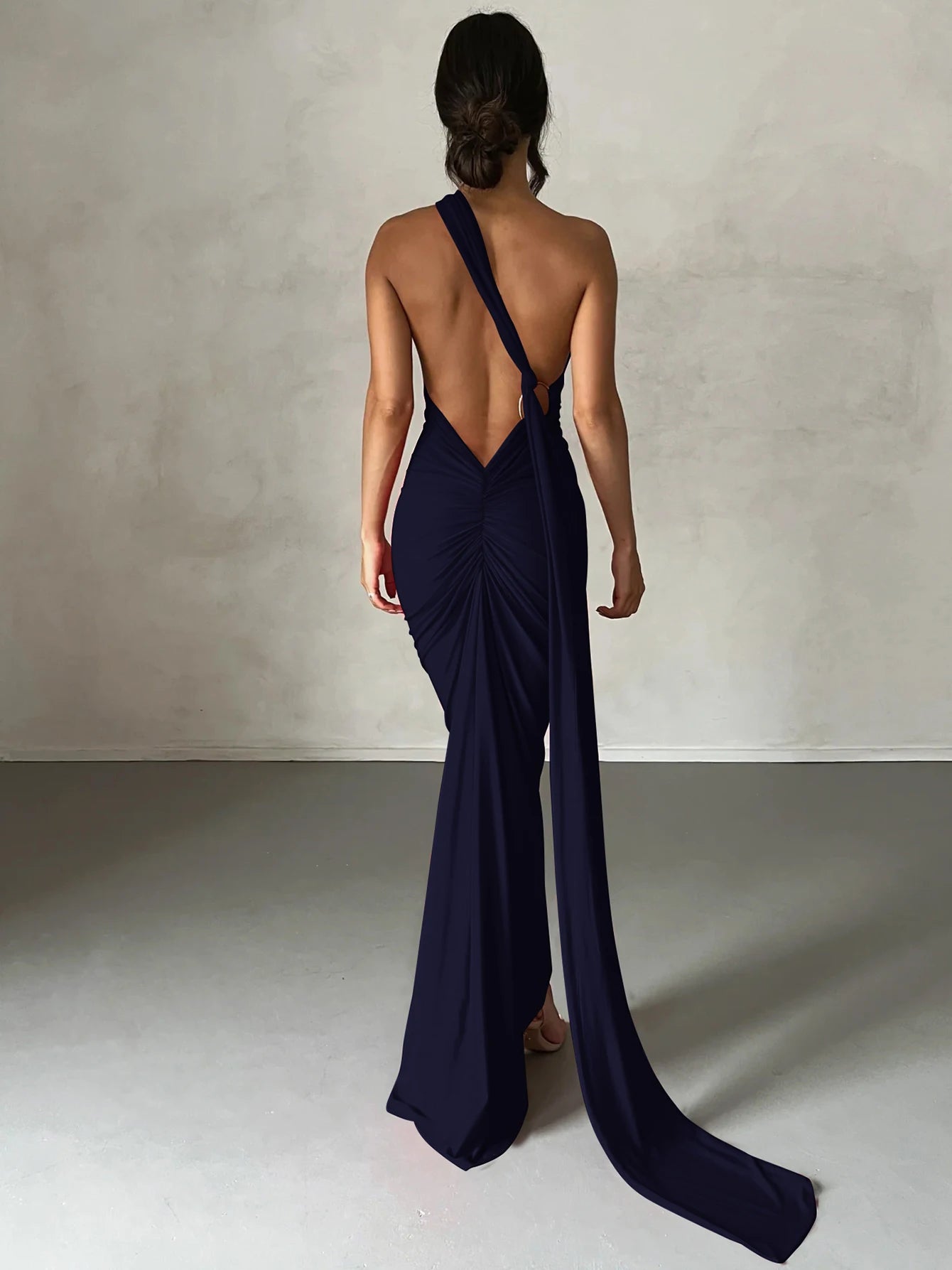 Navy blue evening gown with a long train on a plain background