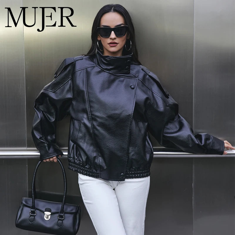 Woman in a black leather jacket and sunglasses holding a black handbag against a metallic background with 'MUJER' branding.