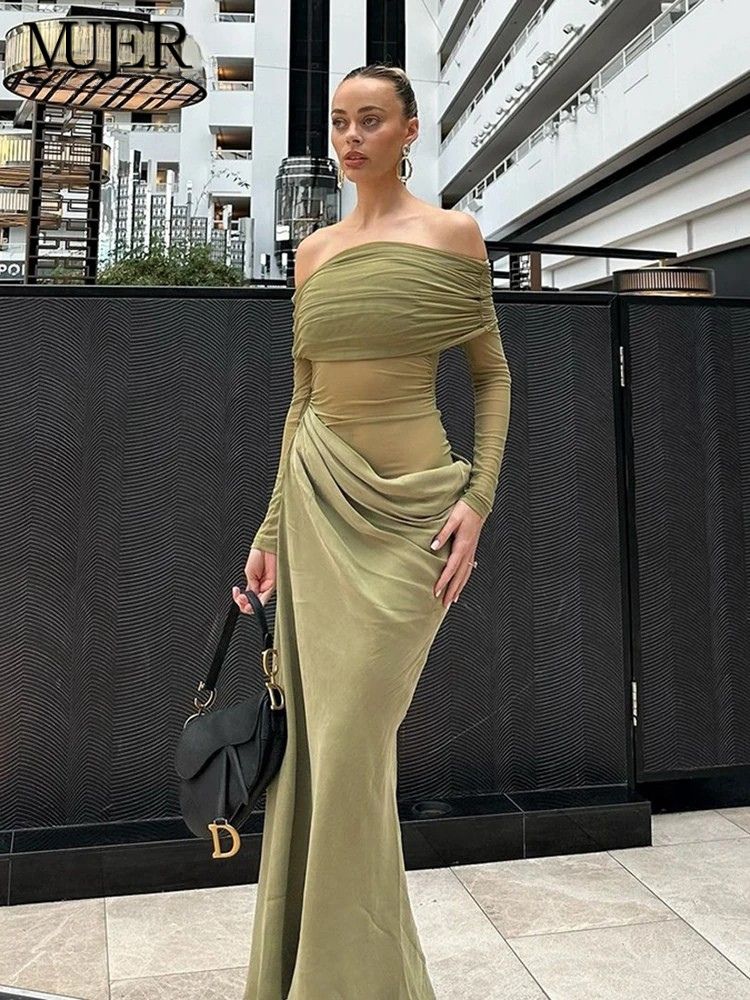 Woman in a green off-shoulder dress standing outdoors with a building in the background