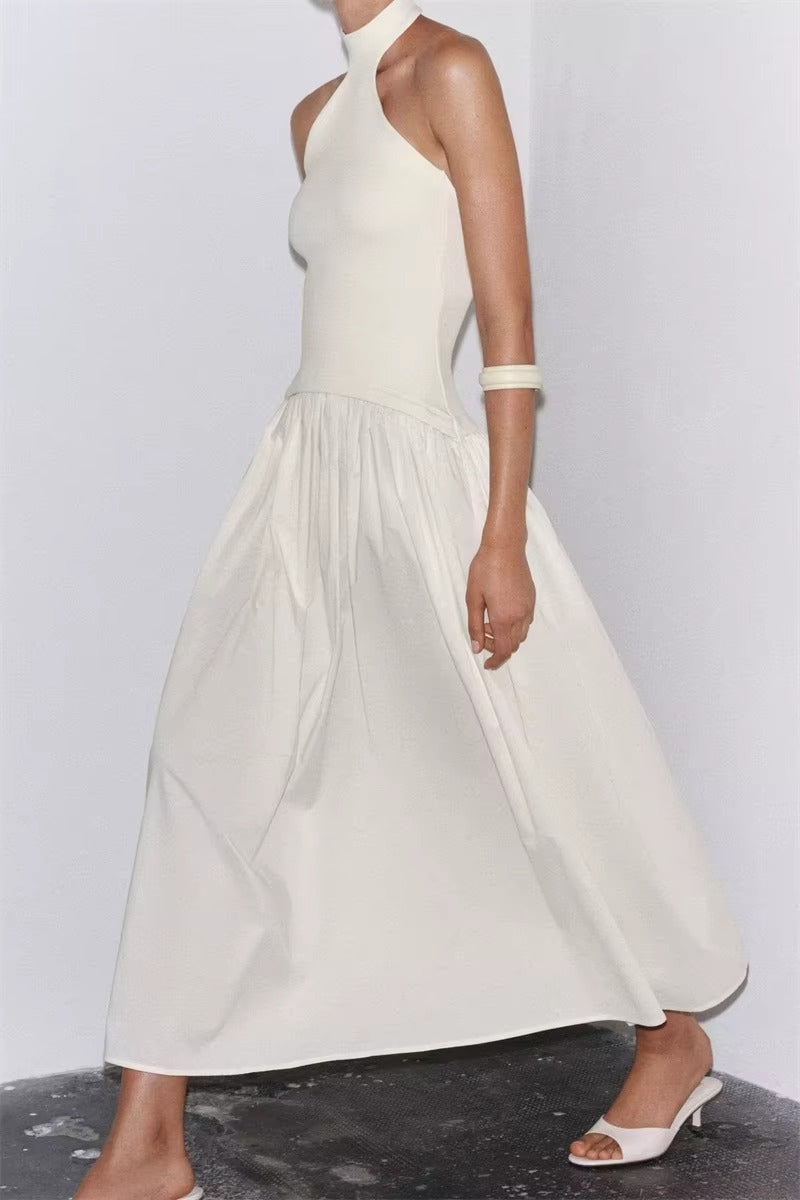 Woman wearing a white halter neck dress on a plain background